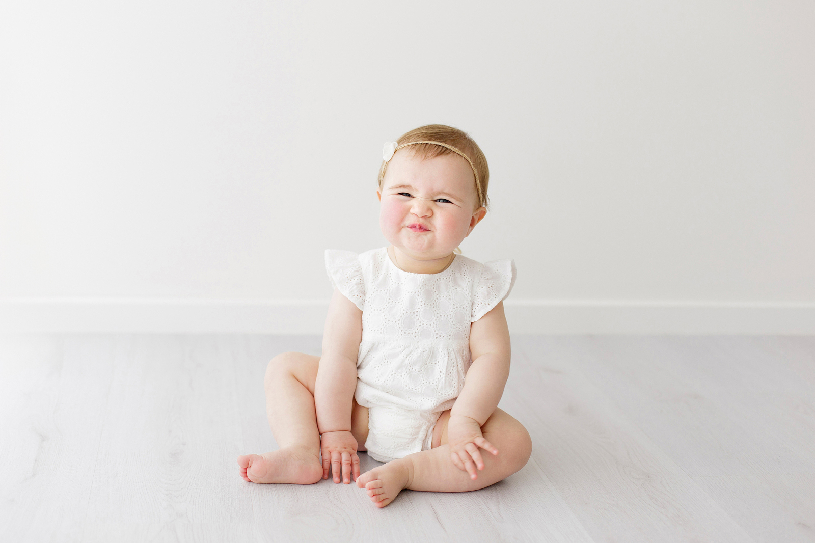 baby in a white outfit smiling.