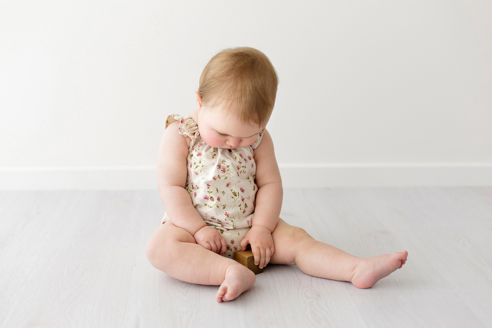 baby in a floral romper playing with blocks-geelong-baby-photographer