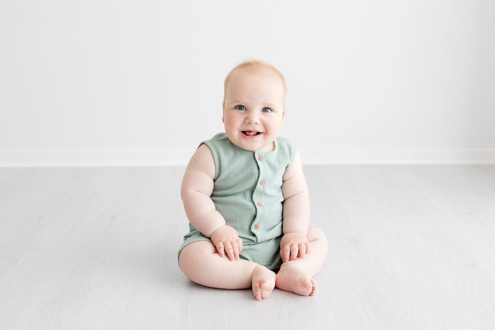 baby in a green romper looking at the camera