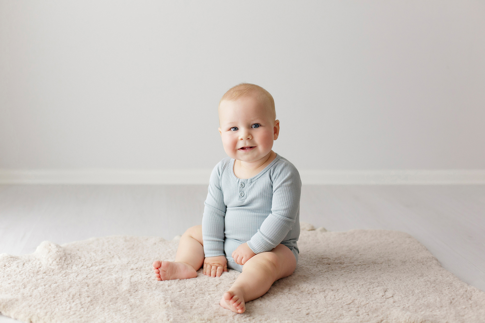 Baby in a long sleeved blue romper, smiling