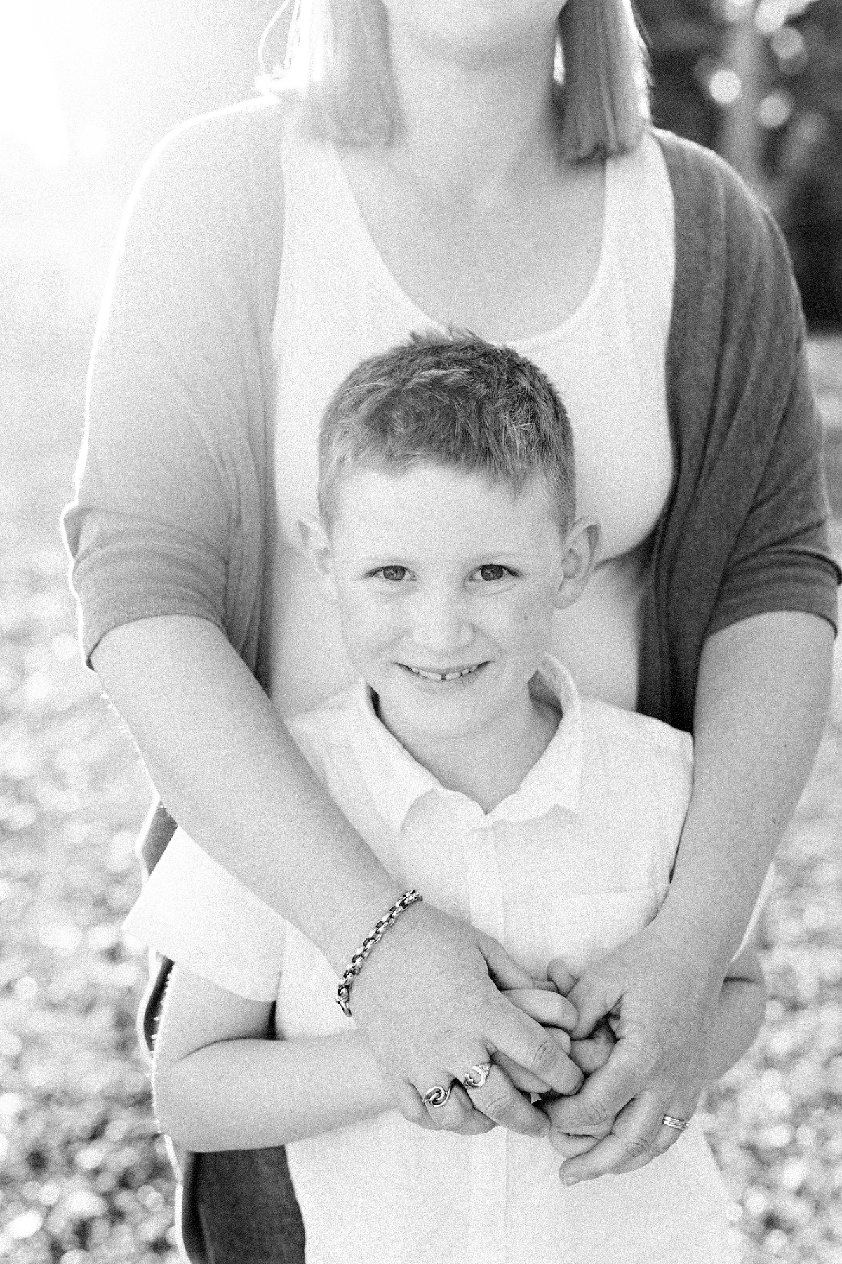 boy smiling holding his mothers hands