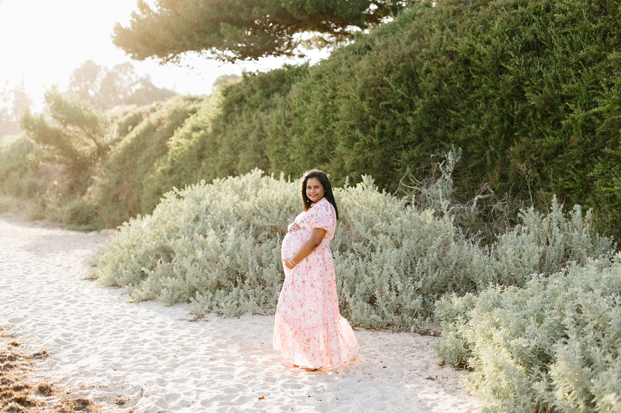 Mum to be on the beach at sunset.